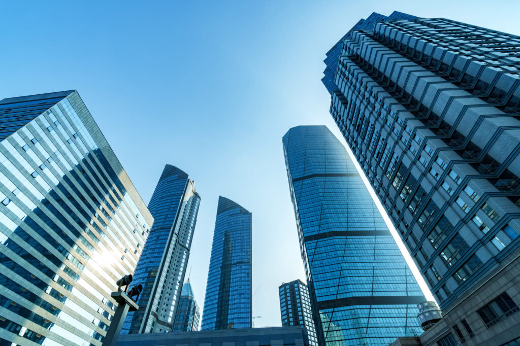 A low-angle photograph shows several modern skyscrapers with glass facades, which are examples of the large commercial properties often used in real estate syndication.